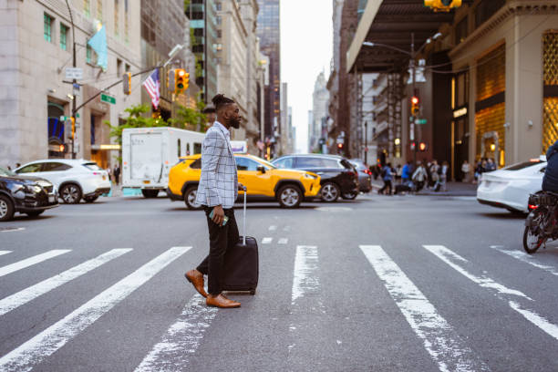 istock Affluent black businessman on a trip to NYC, zebra crossing 1587003938
