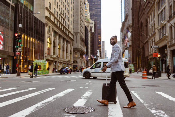 istock Affluent black businessman on a trip to NYC, zebra crossing 1587005094