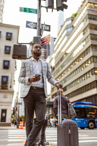 istock Affluent black businessman on a trip to NYC, using mobile phone 1587006711