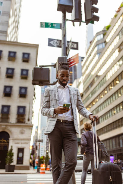istock Affluent black businessman on a trip to NYC, using mobile phone 1587006715