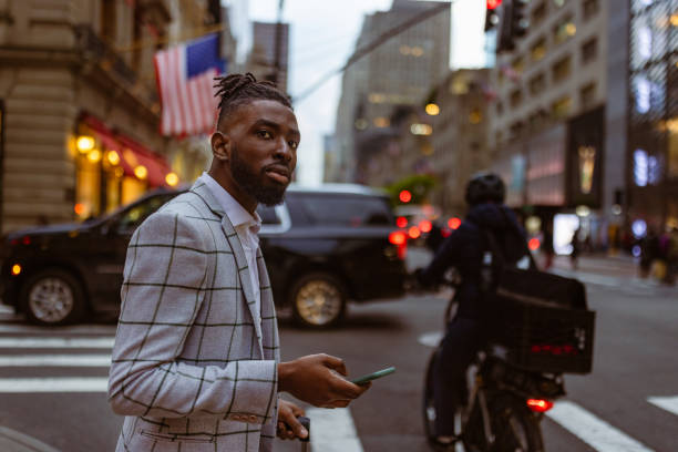 istock Affluent black businessman on a trip to NYC, using mobile phone app calling taxi 1587008358