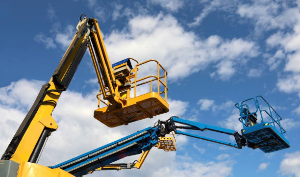 istock Aerial working platforms of cherry pickers against blue cloudy sky. 1587012723
