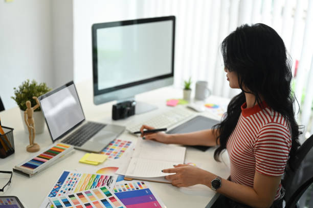 istock Young creative woman working with color palette, choosing color samples for design project at graphic studio. 1587012742