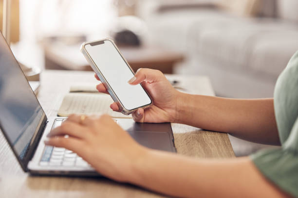 istock Hands, typing on laptop with phone and remote work, freelancer checking email screen or social media mockup. Networking, online research in virtual space and technology with mobile app in home office 1587016452