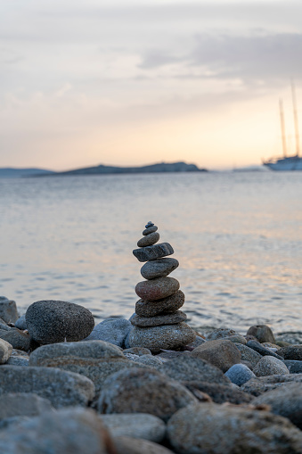 Small inukshuk monument inspired by the Inuit culture, made with rocks on a clear blue sky at sunrise