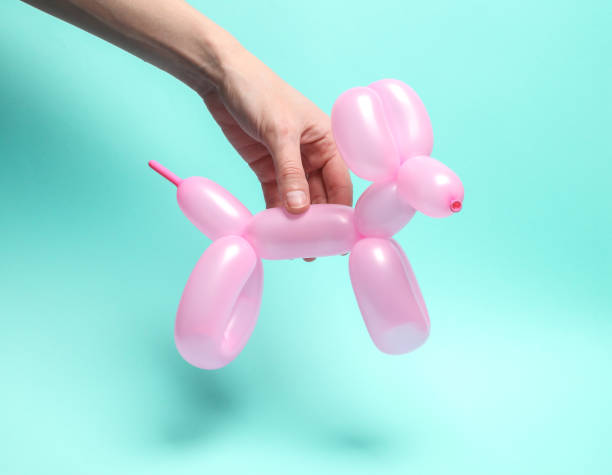 istock Woman's hand holding balloon dog on blue background 1587027396