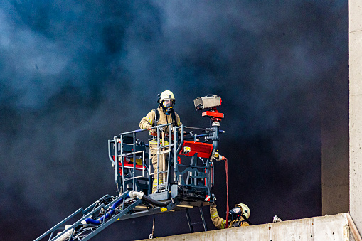 July 28, 2023, Beylikdüzü, Istanbul, Turkiye: Firefighters enter a building in one of the industrial jones, mainly consisting of car mechanics and spare part shops, which is burning in heavy smoke, using a crane to fight the fire.