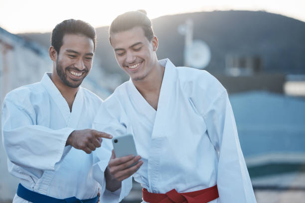 istock Men, martial arts or karate class with phone, thinking or pointing at training video on web for development. Fight workout partnership, smartphone or meme with focus for exercise, coaching or sports 1587037834