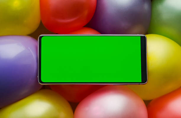 teléfono móvil con una pantalla verde acostada sobre globos de colores - personal organizer meeting business cyberspace fotografías e imágenes de stock