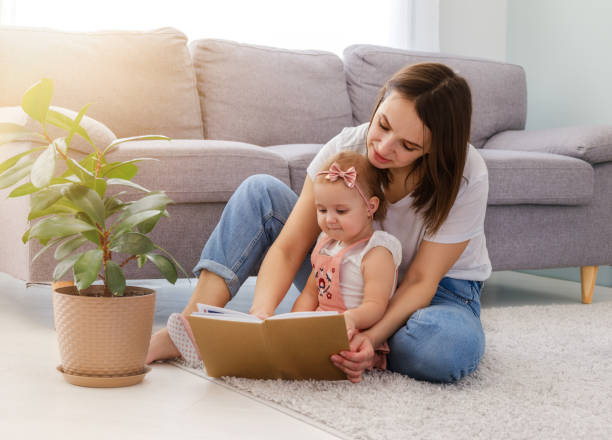 istock pretty young mother reading a book to her daughter 1587041568