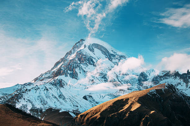 georgien. der gipfel des berges kasbek ist mit schnee bedeckt. erstaunliche georgische naturlandschaft am sonnigen wintertag. erstaunlich kühner, hellblauer himmel. reise nach georgien - kazbek stock-fotos und bilder