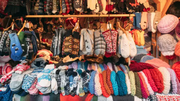 Photo of Crafted Knitted Traditional European Warm Clothes - Mittens At Winter Christmas Market. Souvenir From Europe. Hand Crafted Warm Clothes In Christmas Store. Various Multicolored Mittens And Gloves