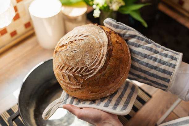 istock Homemade wheat bread in female hands on kitchen background 1587072725