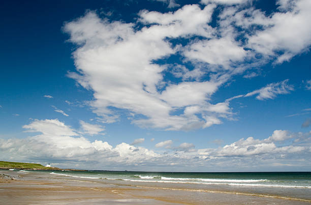 fonds de nuage sur northumberland beach - northumberland england bamburgh lighthouse beach photos et images de collection