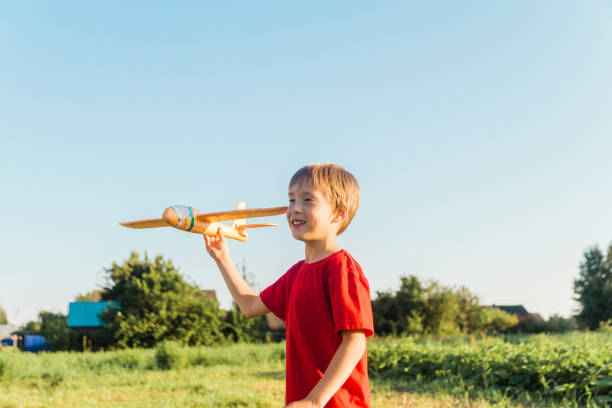 istock A happy boy is playing with a toy airplane outdoors on a sunny summer day. 1587122877