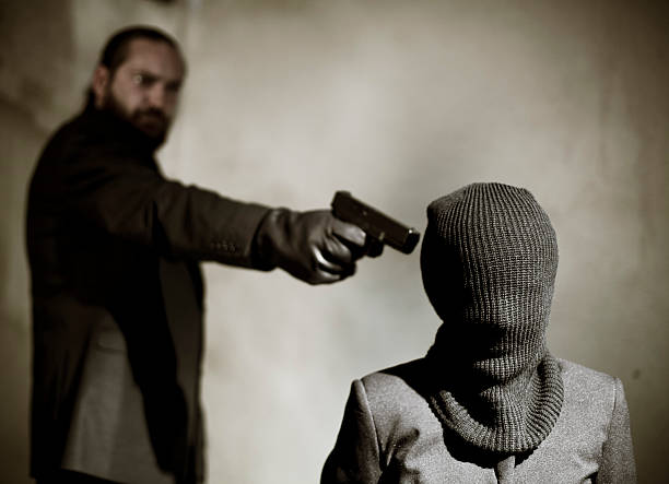 Bearded man pointing a gun at a man's temple to execute him Prisoner being threatened by man with gun torture photos stock pictures, royalty-free photos & images