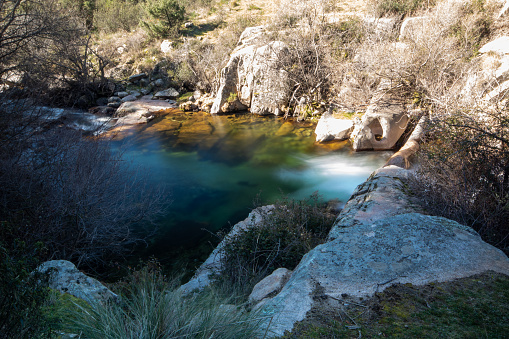 Photograph of the La Pedriza river with a waterfall and crystal clear waters: The image shows the La Pedriza river flowing gently between the rocks, with a beautiful waterfall in the background.
