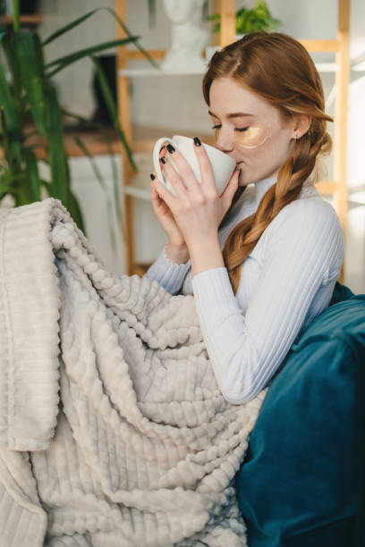 istock Young woman drinking hot beverage 1587145786