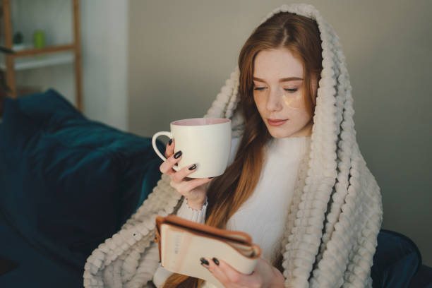 istock Young woman with cup of coffee reading book 1587145789