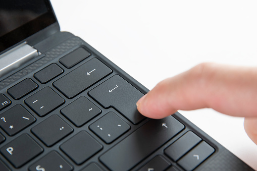 Finger is pushing enter key on computer keyboard