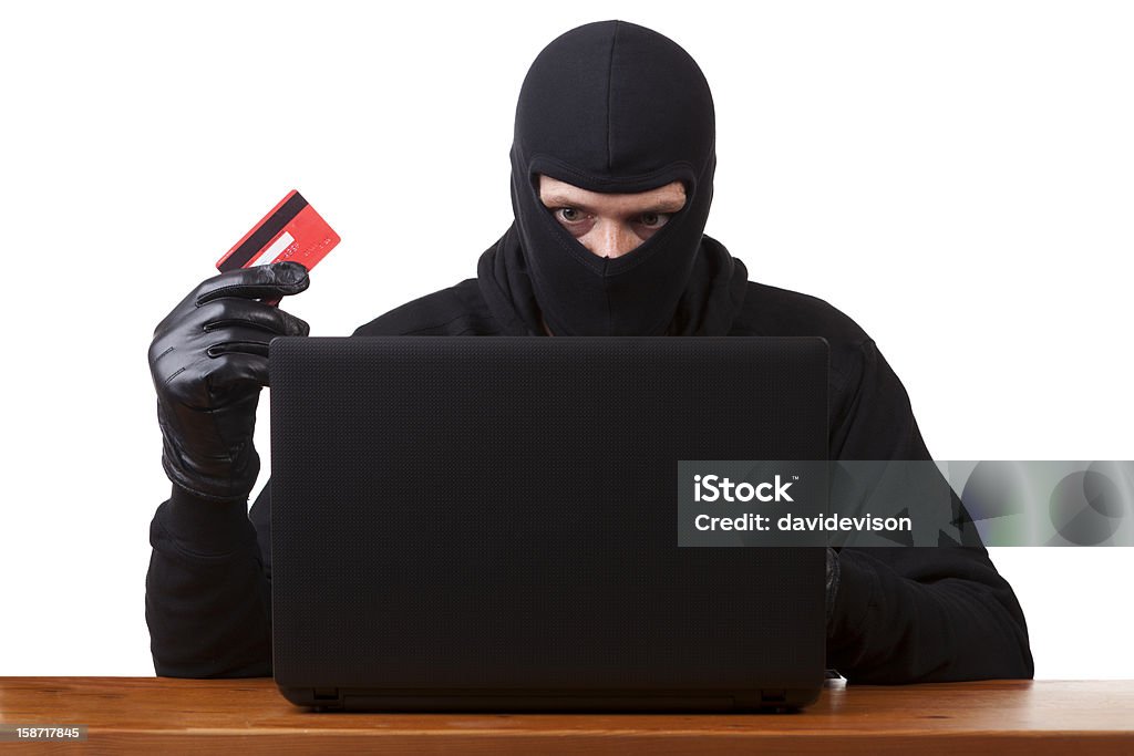 Online theft Masked man using stolen card to shop online. Internet theft concept. Dishonesty Stock Photo