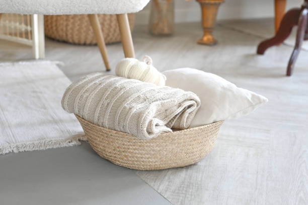 istock Folded knitted beige linen blanket and pillow inside a rustic woven backet. Wicker basket with cozy plaid. Home interior 1587181618