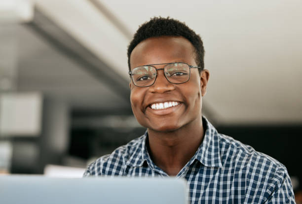 istock Portrait, laptop and it support with a black man working in his office as an engineer or technician. Face, happy and smile with a nerd or geek at work in information technology or internet security 1587191016