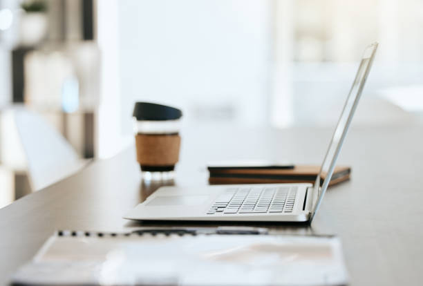 istock Empty table with files, coffee and laptop with notebook, folder and financial portfolio of economy, stock market or trading research. Digital tech for online study of cryptocurrency investment growth 1587196733