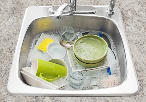Dishwashing. Bright dishes soaking in the kitchen sink.