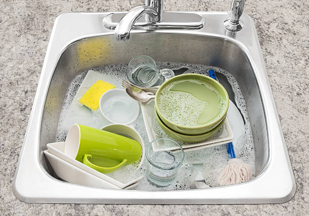 Dishes soaking in the kitchen sink Dishwashing. Bright dishes soaking in the kitchen sink. drenched stock pictures, royalty-free photos & images