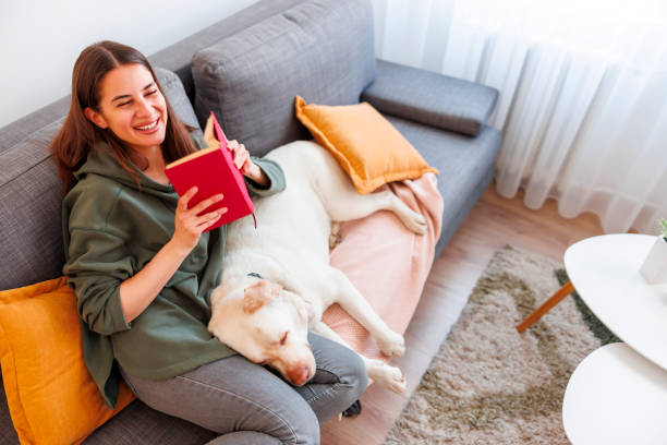 istock Woman reading a book and cuddling her dog 1587235649