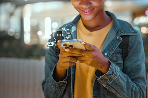 Digital AI chatbot, Happy young African American woman using mobile smartphone with AI chatbot for online information in night town, conversation assistant.