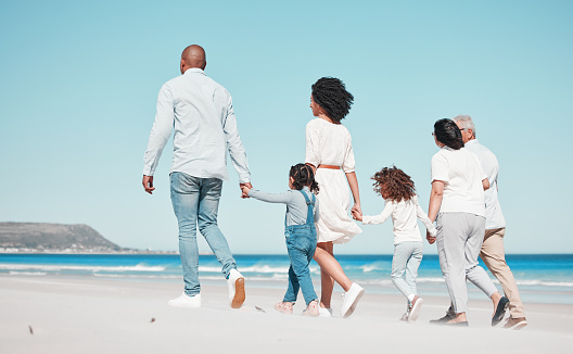 Family, grandparents and children walking on beach to relax on summer holiday, vacation and weekend. Happy, parents and back of mother, dad and kids holding hands for calm, bonding and quality time