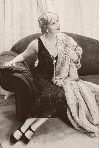 Fancy lady in 1920s style sitting on a luxury chaise-longue - noise has been added for vintage effect