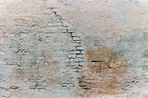 An old Roman wall weathered and deteriorated by time making a grungy textured background. Shot on film.