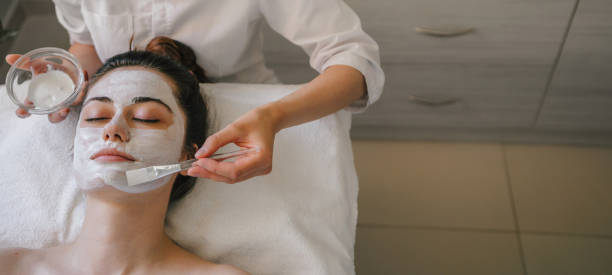 istock Woman applying eye patches on face of client 1587295183