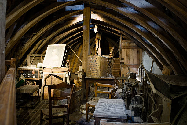 A wooden storage of some old things, papers and stuff, some broken, with webs all around, lit from the small window. On the photo there is an old (at least XIX century) painting (portrait) by unknown author in very bad condition.