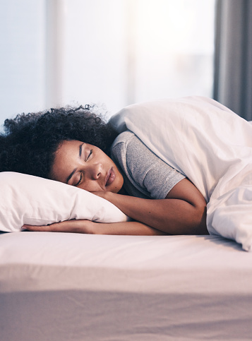 Sleeping, African woman and bed with morning nap in home with rest feeling calm with peace. House, bedroom and tired female person relax and comfortable on a pillow with blanket dreaming on weekend
