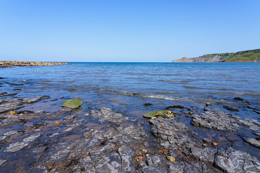 Cloudless spring day on the rocky foreshore of Runswick Bay in North Yorkshire.
