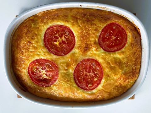 The dish contains chicken, eggs, cream, cheese, and was  garnished with tomato slices and served with bread and a salad.