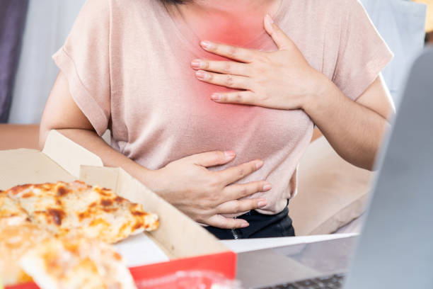 frau leidet an brust, sodbrennen, verursacht durch sauren reflux nach dem pizzaessen - refluxkrankheit stock-fotos und bilder