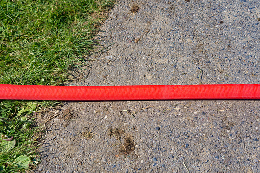 Scenic view of farmland and rural road with close-up view of red irrigation hose at City of Zürich on a sunny late afternoon spring day. Photo taken May 31st, 2023, Zurich, Switzerland.