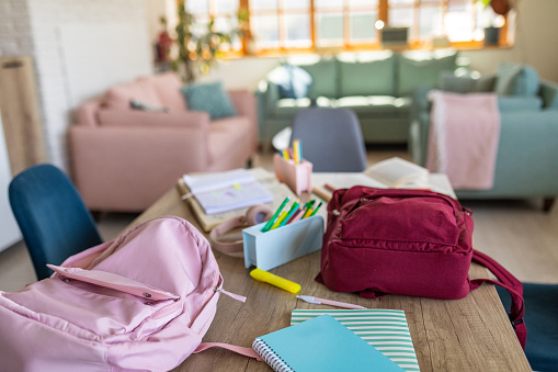 Two backpacks and other school equipment on a table in a room