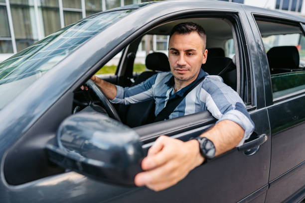 istock Young Man Adjusting His Side-View Mirror In The Car 1587416003