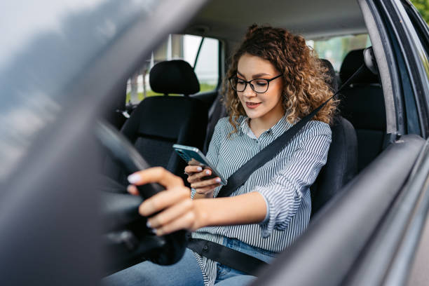 istock Young Woman Using Her Phone While Driving A Car 1587418239
