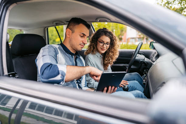 istock Young Driving Instructor Showing His Female Student Driving Test Results On A Tablet 1587421048