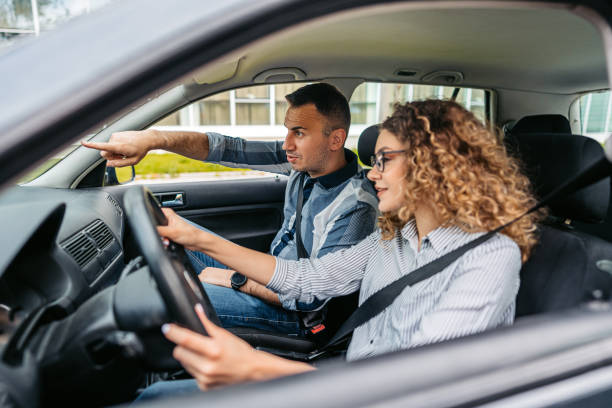 istock Young Woman Having A Driving Lesson With A Male Driving Instructor 1587421579