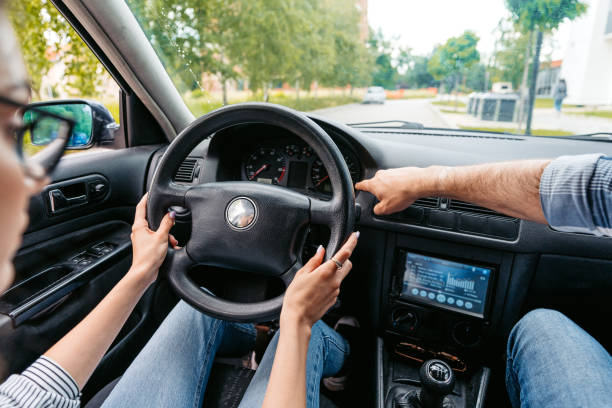 Young woman having a driving lesson with a male driving instructor inside of a car. Close-up.