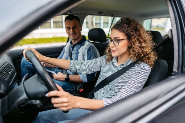 istock Young Woman Having A Driving Lesson With A Male Driving Instructor 1587429351