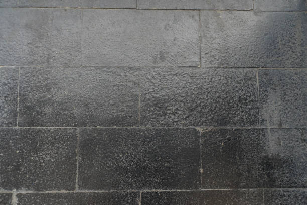 istock Dark grey brick stone tile wall texture detail closeup 1587437440